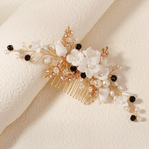 Détail d'un peigne de mariée avec fleurs en céramique, perles et branches dorées