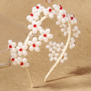 Close-up of handmade bridal headband with white pearl petals and red crystal centers