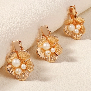 Détail de trois barrettes fleurs dorées avec perles et pétales à rainures radiales fines