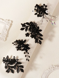 Détail de pinces à cheveux fleurs noires avec perles et pompons pour soirées