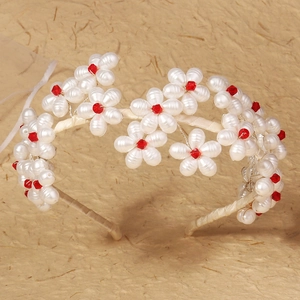 Detailed macro view of handmade bridal headband with red crystal flowers and white beads