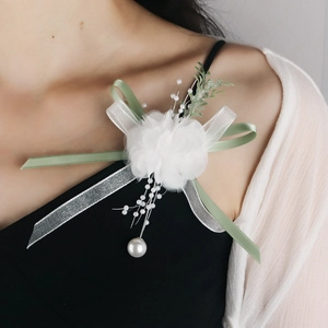 Detail of white handmade floral brooch with pearls and sage green ribbons on a black dress