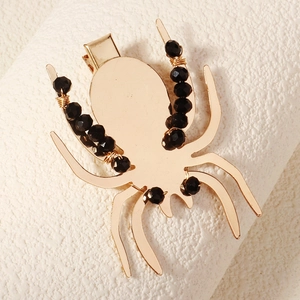 Détail d'une pince à cheveux araignée dorée avec perles noires et clip en métal