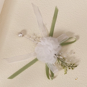 Detail of handmade white flower boutonniere with silk ribbons and pearl pin for weddings