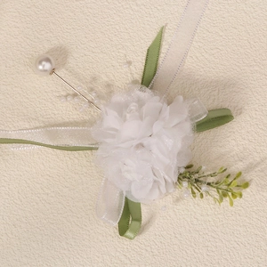 Detailed macro view of a white fabric flower brooch with pearls and green ribbons