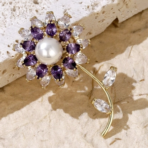 Detailed view of luxury flower brooch with purple gemstones, pearl and golden leaves