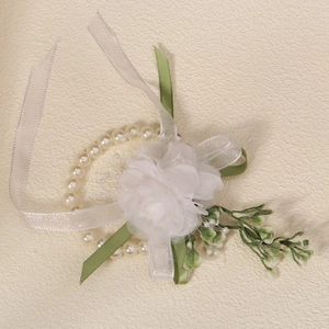 Detail of white silk floral wrist corsage with faux pearls and green ribbon accents