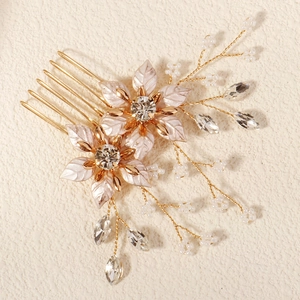 Detailed close-up of golden metal hair comb with white enamel flowers and pearls
