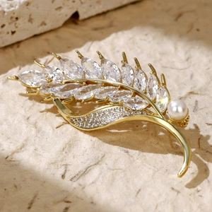 Detail of a golden wheat brooch with zircon stones and a central white pearl inlay