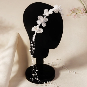 Détail de fleurs en tissu blanc et de glands de perles en cascade sur un bandeau de mariée