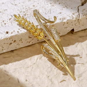 Macro detail of wheat brooch with golden ears and zircon crystals on natural stone