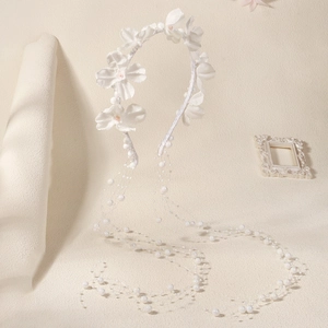 Détails du serre-tête de mariée avec fleurs en tissu blanc et pampilles de perles fines