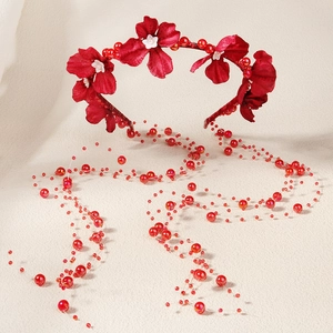 Détail du bandeau floral rouge avec fleurs en tissu et longues chaînes de pompons perlés