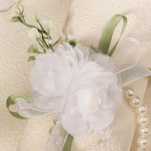 Elegant white floral bridal wrist corsage with pearls and green leaves for wedding parties