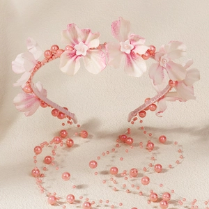 Détail de fleurs en tissu rose et franges de perles sur un bandeau floral doux