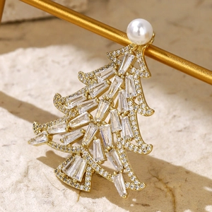 Macro shot of gold-plated Christmas tree brooch featuring cubic zirconia and pearl