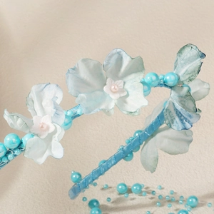 Vue macro détaillée de fleurs en tissu bleu clair et perles sur un serre-tête mariée
