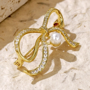 Macro shot of gold-plated bow brooch with sparkling zircons and a round white pearl