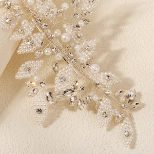 Détail d'un peigne de mariage fait main avec perles et feuilles de cristal sur fil argenté