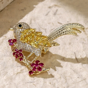 Macro shot of bird brooch with yellow marquise gems and white zircons on golden branch