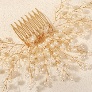 Close-up of handmade bridal hair comb with gold wires, pearls and transparent beads