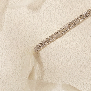 Close-up of luxury bridal belt with double-row sparkling rhinestones and white organza ribbon