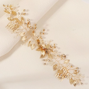 Détail du peigne à cheveux mariée avec feuilles dorées, perles blanches et strass brillants