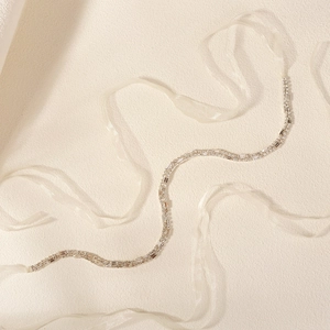 Detail of double-row rhinestone bridal belt with cream organza ribbon on neutral background