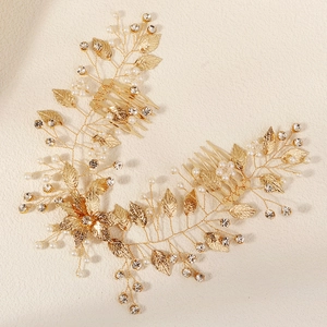Détail d'un peigne à cheveux de mariée doré avec strass, feuilles en métal et perles