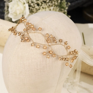 Close-up of golden floral bridal headband with delicate crystals and white satin ribbon