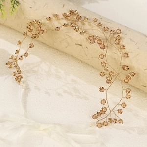 Close-up of handmade gold metal flowers and crystals on a bridal wedding headband hair vine