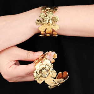 Close-up of golden floral cuff bracelet with detailed petal textures on female wrist
