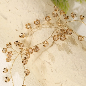 Detailed close-up of handmade gold metal floral headband with crystal accents