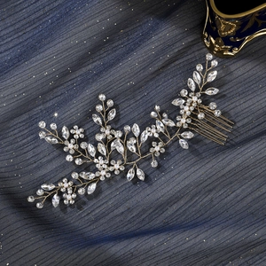 Detailaufnahme des funkelnden Braut-Haarkamms mit goldenen Blumenzweigen und Perlen