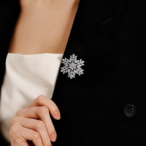 Close-up of a silver snowflake brooch with sparkling rhinestones on a black suit lapel