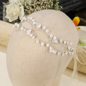 Close-up of handmade bridal headband with white flowers and silver wire on mannequin