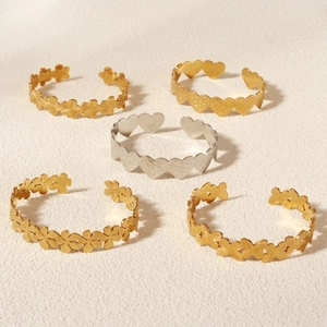 Detail of five adjustable metal bangles with floral and heart patterns in gold and silver