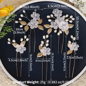 Detailed view of bridal hair pin set with white acrylic flowers and gold metal leaves