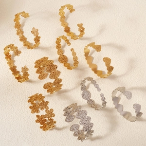 Detail view of retro leaf and flower metal bracelets with embossed textures in gold and silver