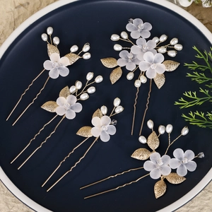 Detail view of 5-piece bridal hair pins with white acrylic flowers and gold leaves
