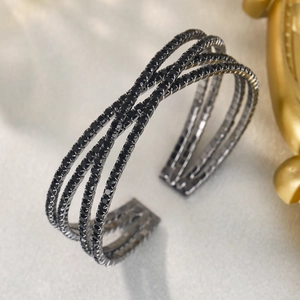 Détail macro du bracelet manchette croisé en métal noir avec strass noirs brillants