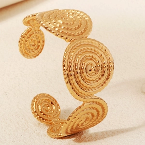 Macro detail of gold textured spiral discs on a vintage style open cuff bracelet for women