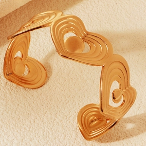 Macro detail of golden open heart cuff bracelet with textured ripple pattern