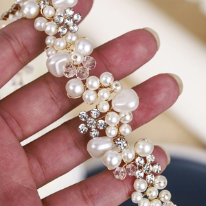Détail d'un serre-tête de mariée fait main avec perles, cristaux et fleurs dorées