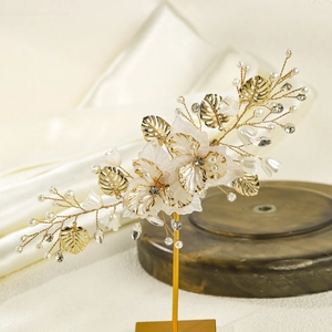 Detail of handcrafted bridal hair clip with gold leaves, white resin flowers and pearls