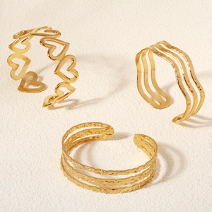 Three-piece gold metal cuff bracelet set with heart patterns and textured wave designs