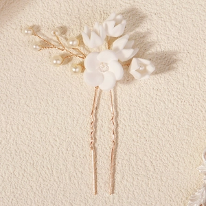 Nahaufnahme der Braut-Haarnadel mit weißen Tonblumen, Golddraht und Kunstperlen