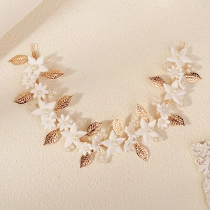 Close-up of flexible gold bridal hair vine with white clay flowers and pearls