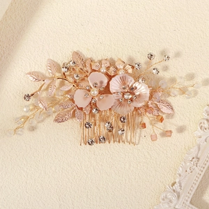 Détail d'un peigne à cheveux de mariée avec fleurs en émail rose et perles blanches