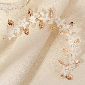 Close-up of handmade bridal hair vine with white clay flowers and golden leaves